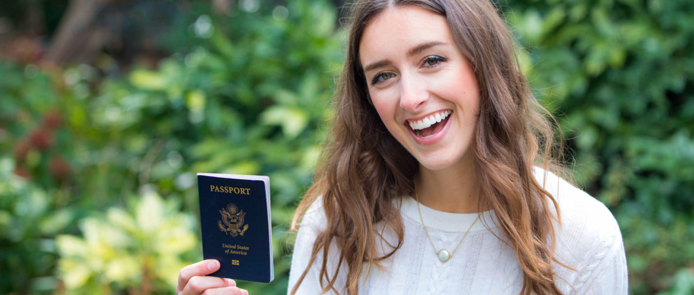Posing with a passport and globe for Ellen Blazer's travel blog To Travel and Bloom
